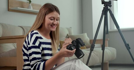 Young beautiful professional photographer reviewing shots on modern camera indoors - Powered by Adobe
