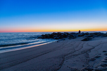 Blue hour on the beach with rocks in the water, long exposure