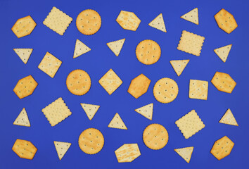 Food pattern of crispy crackers of different shapes isolated on a bright blue background. Top view,...
