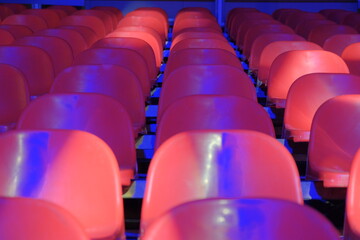 Naklejka premium red plastic grandstand chairs under blue light