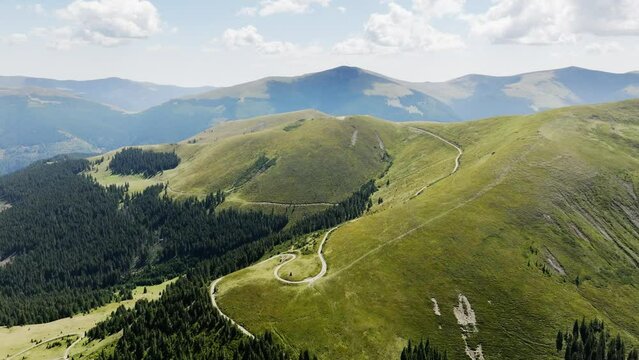 Aerial view of the Transalpina road in Romania. Carpathian Mountains, curvy road, summer, green trees, drone, highlands, scenery, road trip, highway, valleys. 4K 50fps Drone Video Footage