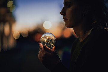 young worried female human holding bright shining lightbulb in her hands feeling unsave while...