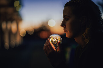 young worried female human holding bright shining lightbulb in her hands feeling unsave while...