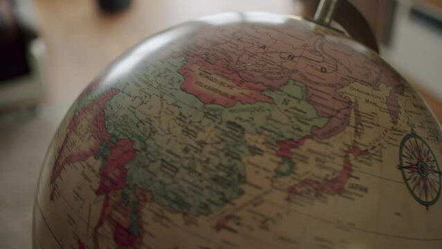 Close up shot of a hand spinning a vintage globe and landing on East Asia.