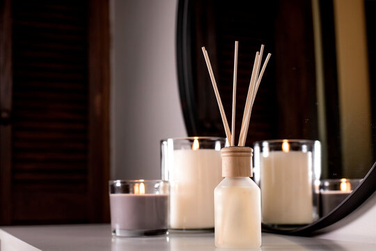 Air freshener in a glass bottle and scented candles in candle holders. Home atmosphere. Fragrances for the home