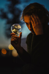 young worried female human holding bright shining lightbulb in her hands feeling unsave while...