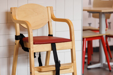 Wooden dinning chair with safety seat belts for baby. wooden high chair for kid eating in asian restaurant. - Powered by Adobe