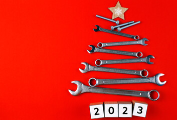 Christmas tree made of tools with wooden cubes "2023" on a red background