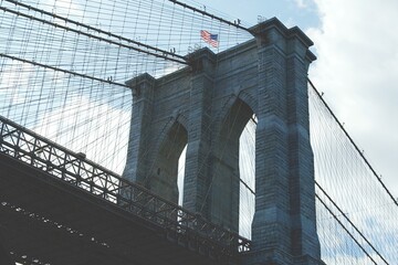 Close-up of the Brooklyn Bridge with blue sky and clouds in the background.