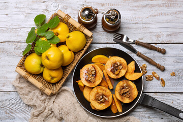 A dish of quince in a frying pan with spices on a light wooden table