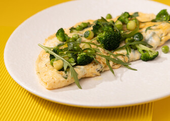 amlet with egg and greens on a white plate on a yellow background
