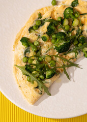 amlet with egg and greens on a white plate on a yellow background