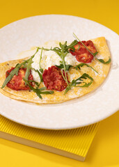 amlet with egg and greens on a white plate on a yellow background