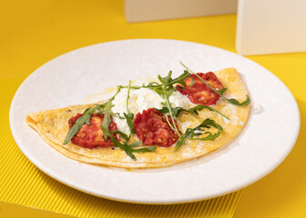 amlet with egg and greens on a white plate on a yellow background