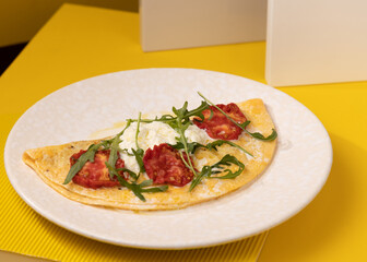 amlet with egg and greens on a white plate on a yellow background