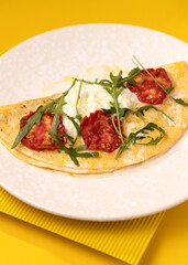 amlet with egg and greens on a white plate on a yellow background
