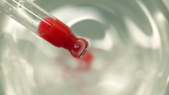 Red liquid falling from the pipette into the water