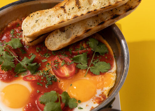 amlet with tomato and toast in a frying pan on a yellow background