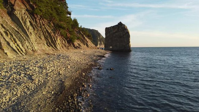 Lonely rock in the form of a wall on the seashore, drone flight