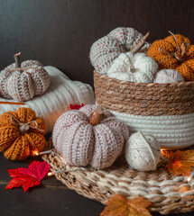 white, beige and yellow handmade crochet pumpkins with autumn leaves , crochet hook, woolen balls on dark brown wooden ground