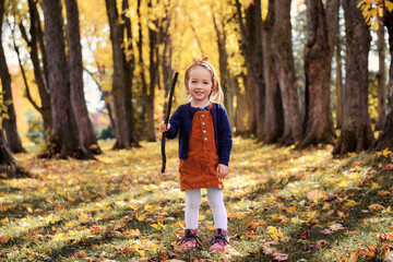 Adorable two years old girl enjoying nice and sunny autumn day outdoors