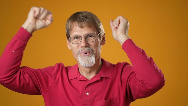 Mature man unsure guy in red shirt shrugs his arms, makes gesture of I dont know, cant help anything isolated on solid yellow background.