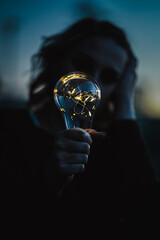 young worried woman holding bright shining lightbulb in her hands feeling unsave while in fear...
