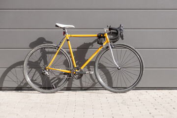 Naklejka na ściany i meble vintage yellow racing bike leaning against a gray wall