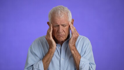 Sick ill tired headache elderly gray-haired man 70s wears blue shirt rub forehead suffer from migraine feel bad seedy isolated on plain light purple background studio portrait