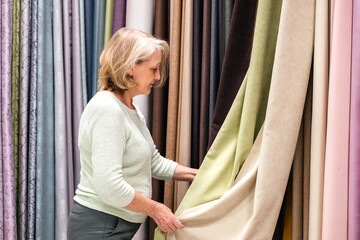 Woman choosing curtains in textile store indoor. Designer working and combining colors and textures