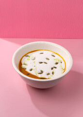 pumpkin cream soup on a pink background
