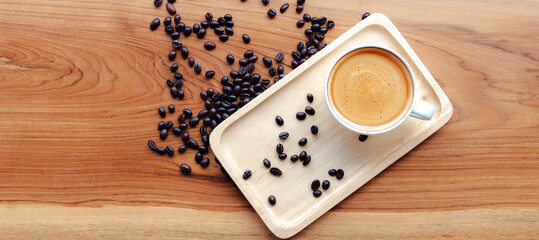 Top view of the white cup of espresso coffee and Roasted coffee beans on wooden background