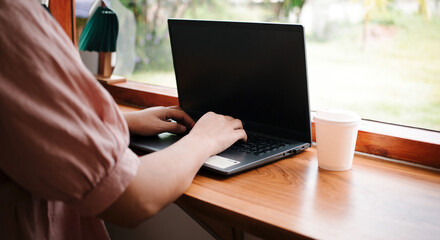 Close-up of woman's hands typing on a laptop.businesswoman working on a laptop, old or lady using computer concept writing emails, communicating online, while sitting at a table in a cozy cafe.