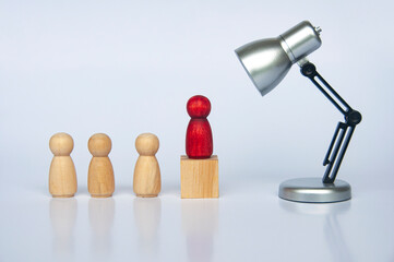 Table lamp focus on red wooden people figure on top of wooden cube leading the people figure. Leadership concept