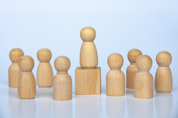 Wooden people figure on top of wooden cube leading the rest of the wooden figure.