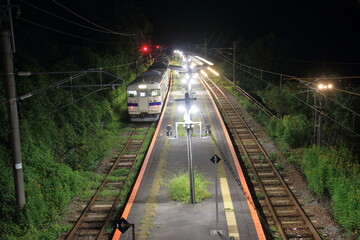 深夜の無人駅で通過を待つ普通列車