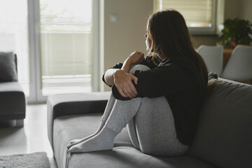 Caucasian sad woman sitting on the sofa and looking away