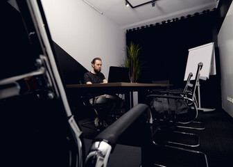 a man in casual clothes is working at a laptop in the office