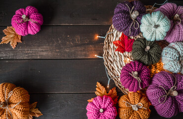colorful handmade crochet pumpkins with lights and autumn leaves on dark brown wooden ground