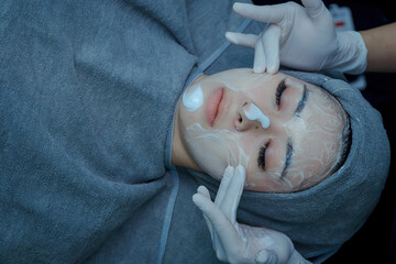 The female dermatologist do face massaged to beautiful girl cosmetology cabinet or beauty clinic. Concept of face cleanser, skin and health care