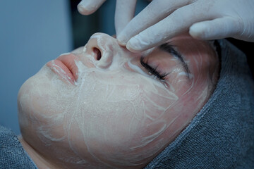 Naklejka premium The female dermatologist do face massaged to beautiful girl cosmetology cabinet or beauty clinic. Concept of face cleanser, skin and health care