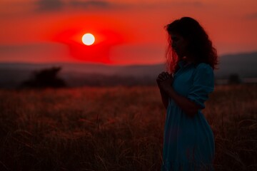 Christian woman prayer to god on field background.