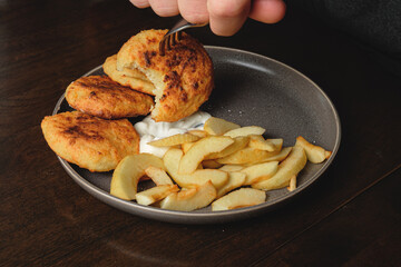 А man eats curd fritters with a fork. Cottage cheese pancakes,curd fritters with fresh apple slices  and sour cream in a dish. Gourmet Breakfast
