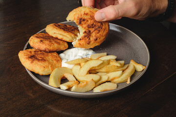 A man eats curd fritters with his hands .Cottage cheese pancakes,curd fritters with fresh apple...