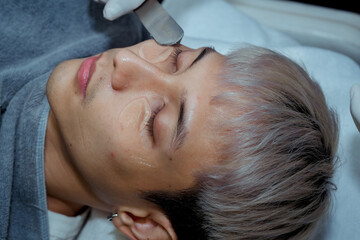 Beautician applying hydro gel mask on the young man face, before laser treatment in beauty salon. Close up side view. , Beauty clinic concepts.