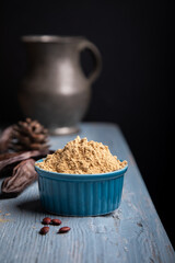 Carob pods and carob powder over a blue wooden background.