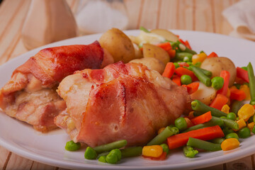 Chicken wrapped in bacon, with vegetables and potatoes.