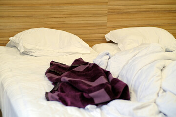 Bed with pillows and crumpled blanket. Crumpled blanket and pillows on empty rumpled bed in hotel room after sleeping in night