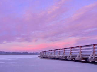 Fototapeta premium Pier on a frozen lake. Sunset over a frozen lake.