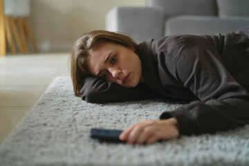Caucasian nervous woman lying down on the floor and waiting for message - obrazy, fototapety, plakaty